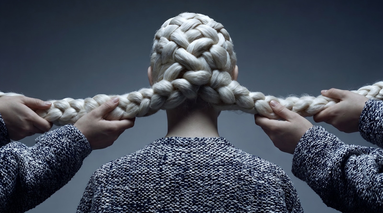 A close view of hands braiding long white hair